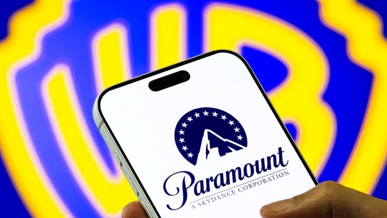 Logotipo da Paramount exibido em smartphone com símbolo da Warner Bros desfocado ao fundo em montagem corporativa