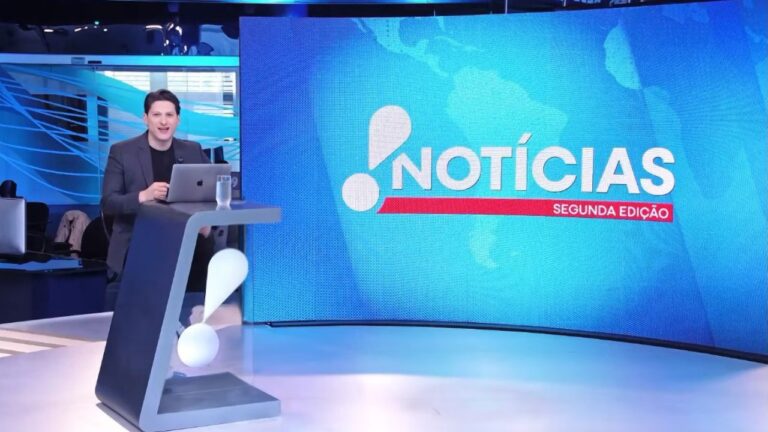 Willian Kury apresenta o RedeTV! Notícias Segunda Edição em estúdio com telão do telejornal ao fundo