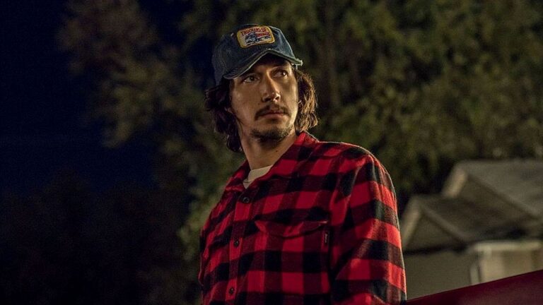 Adam Driver com camisa xadrez vermelha e boné em cena de filme