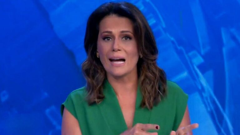 Adriana Araújo apresenta telejornal da Band usando vestido verde diante de telão com gráfico em tons de azul