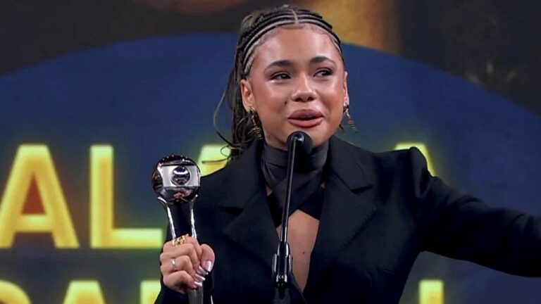 Alana Cabral recebe troféu e discursa ao microfone durante cerimônia de premiação da TV Globo