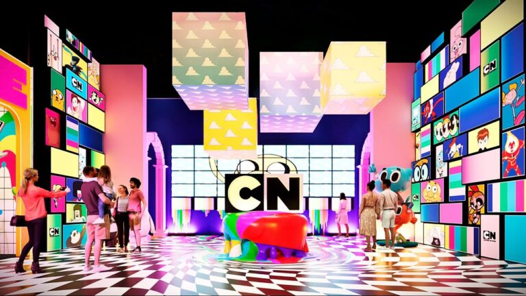 A CN Land será uma das atrações das férias escolares de julho no Shopping Center Norte, em São Paulo. A experiência interativa levará ao público cenários inspirados em animações do Cartoon Network, reunindo ambientes temáticos, recursos tecnológicos e percursos de aventura baseados em personagens conhecidos de diferentes gerações. Segundo a organização, a CN Land foi desenvolvida para ir além de uma exposição tradicional. A proposta combina cenografia, atividades interativas e experiências multissensoriais inspiradas em séries como Ben 10, Laboratório de Dexter, Hora da Aventura, O Incrível Mundo de Gumball e Apenas um Show. CN Land reúne atrações para todas as idades Danielle Paulino, executiva da 2a1, explicou que o objetivo é aproximar o público dos universos das animações. “Nosso objetivo com a CN Land é extrapolar os limites da tela e permitir que o público, de diferentes gerações, sinta que realmente faz parte desses universos”, afirmou. Ela acrescentou que a experiência foi planejada para atender tanto crianças quanto adultos que acompanharam os desenhos ao longo dos anos. “Unimos a nostalgia dos personagens clássicos com o que há de mais moderno em tecnologia interativa e cenografia ponta a ponta, garantindo uma experiência memorável”, declarou. Exposição terá circuitos e desafios A programação contará com atrações inspiradas em diferentes produções do Cartoon Network. Em Ben 10, os visitantes encontrarão uma arena com plataforma giratória em 360 graus e jogos temáticos do Omnitrix. Hora da Aventura oferecerá desafios de arremesso e sistema de pontuação, enquanto As Meninas Superpoderosas terá estruturas suspensas que simulam voos sobre Townsville. A experiência ainda contará com um espaço dedicado a O Incrível Mundo de Gumball, equipado com tobogã e piscina de bolinhas, além de um circuito de aventura inspirado em Apenas um Show. Também fazem parte da exposição ambientes baseados em Urso sem Curso, Coragem, o Cão Covarde e Steven Universe, com atividades voltadas ao equilíbrio, desafios interativos, experiências sensoriais e espaços preparados para fotos e vídeos.