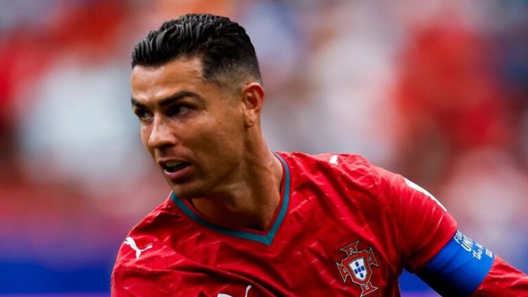 Cristiano Ronaldo com camisa vermelha da seleção de Portugal e braçadeira azul durante partida de futebol olhando para o lado