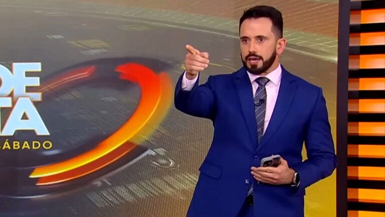 Dionísio Freitas aponta para a câmera enquanto apresenta o Jornal da Band aos sábados em estúdio da emissora