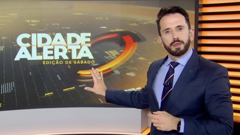 Dionísio Freitas, de terno azul, aponta para painel do Cidade Alerta no estúdio da Record
