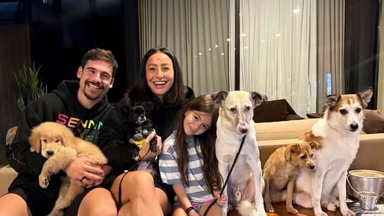 Sabrina Sato, Nicolas Prattes, Zoe e seis cães posam sorrindo juntos na sala de casa