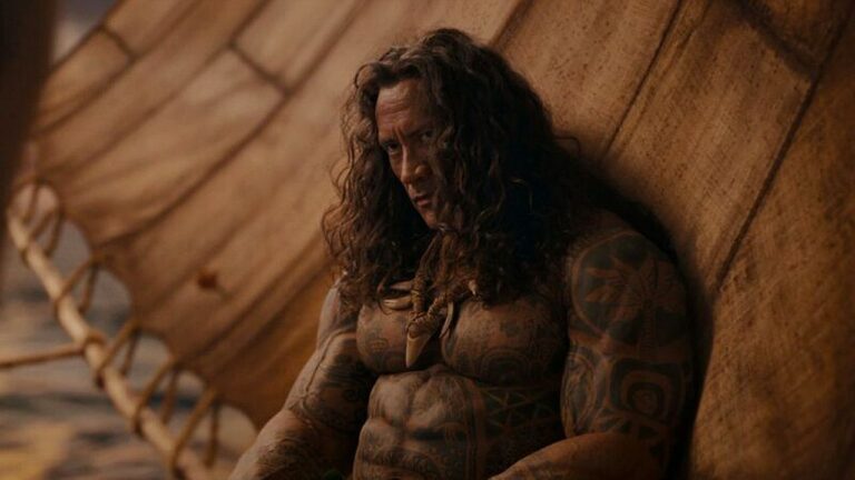 Dwayne Johnson caracterizado como Maui com cabelos longos e tatuagens em cena da adaptação de Moana