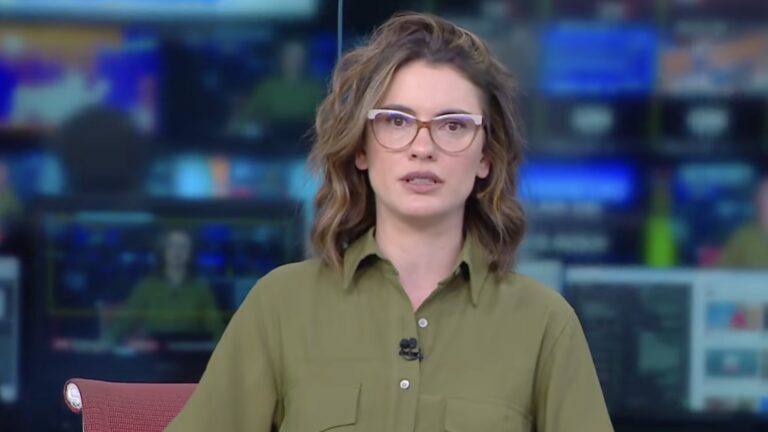 Elisa Veeck, de blusa verde e óculos, apresenta telejornal em estúdio da CNN Brasil