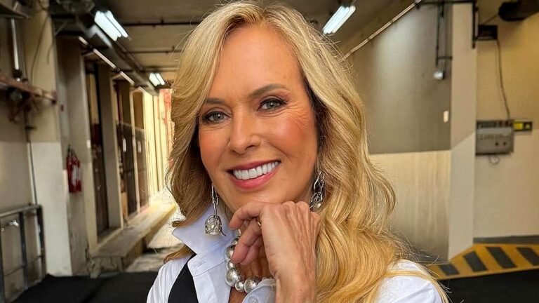 Helô Pinheiro sorri nos bastidores de gravação usando camisa branca e acessórios prateados