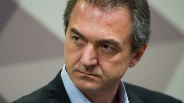 Joesley Batista de terno escuro e camisa azul olha para o lado com expressão séria em retrato de close-up