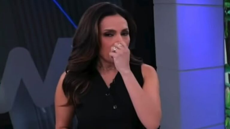 Márcia Dantas leva a mão ao rosto, com expressão de choro, no estúdio do Tempo Real
