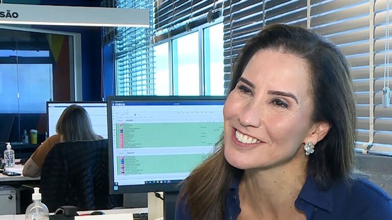 Marcia Dantas sorri durante entrevista em uma redação com computadores ao fundo