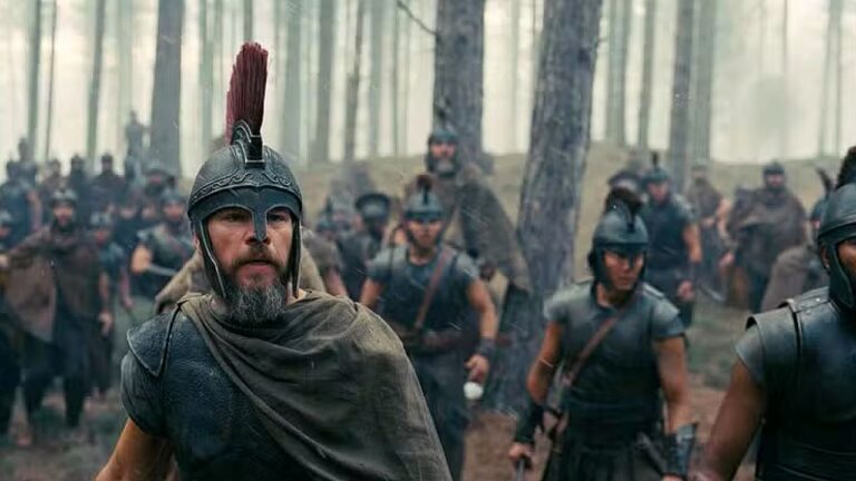 Matt Damon com armadura e capacete lidera soldados em cena de batalha no filme A Odisseia