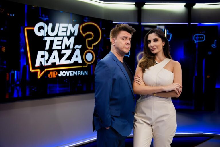 Oscar Filho de terno azul e Paula Nobre de macacão claro posam de braços cruzados em estúdio diante do telão com logo do programa Quem Tem Razão?