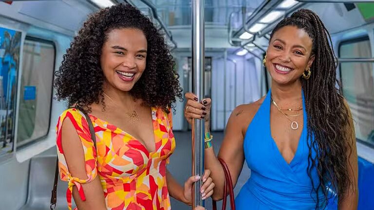 Duas mulheres sorriem dentro de vagão de metrô em cena da novela Por Você