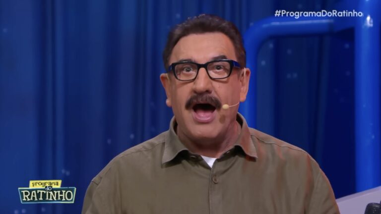 Ratinho, de camisa verde e óculos, fala com expressão surpresa no palco do Programa do Ratinho