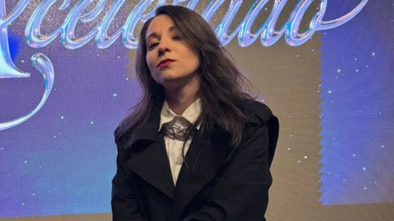 Yrla Braga caracterizada como Rosinha posa diante do painel de Coração Acelerado em foto de divulgação da novela