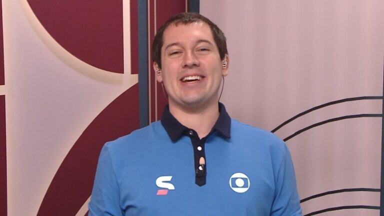 Sergio Arenillas de camisa polo azul sorri em estúdio com ponto eletrônico e painel geométrico ao fundo