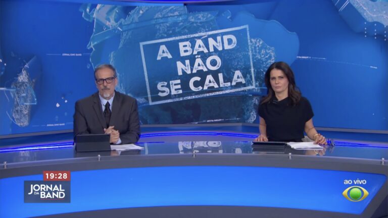 Sérgio Gabriel e Adriana Araújo na bancada do Jornal da Band, com painel A Band Não Se Cala ao fundo