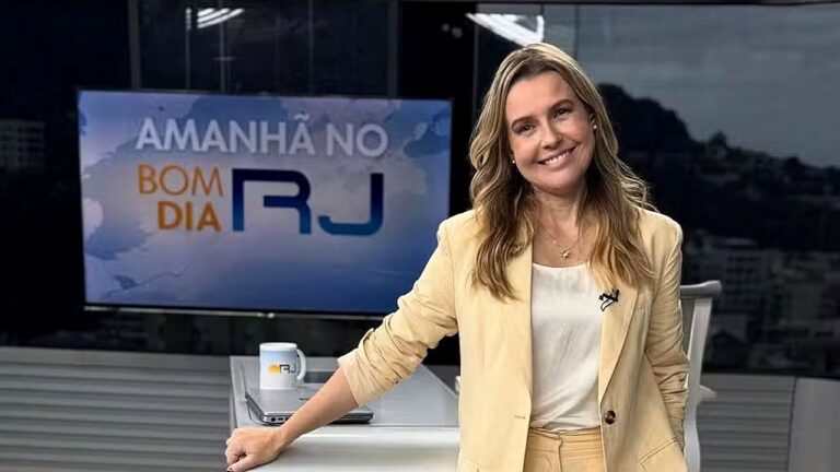 Silvana Ramiro sorri no estúdio do Bom Dia RJ diante da bancada e da tela do telejornal da TV Globo