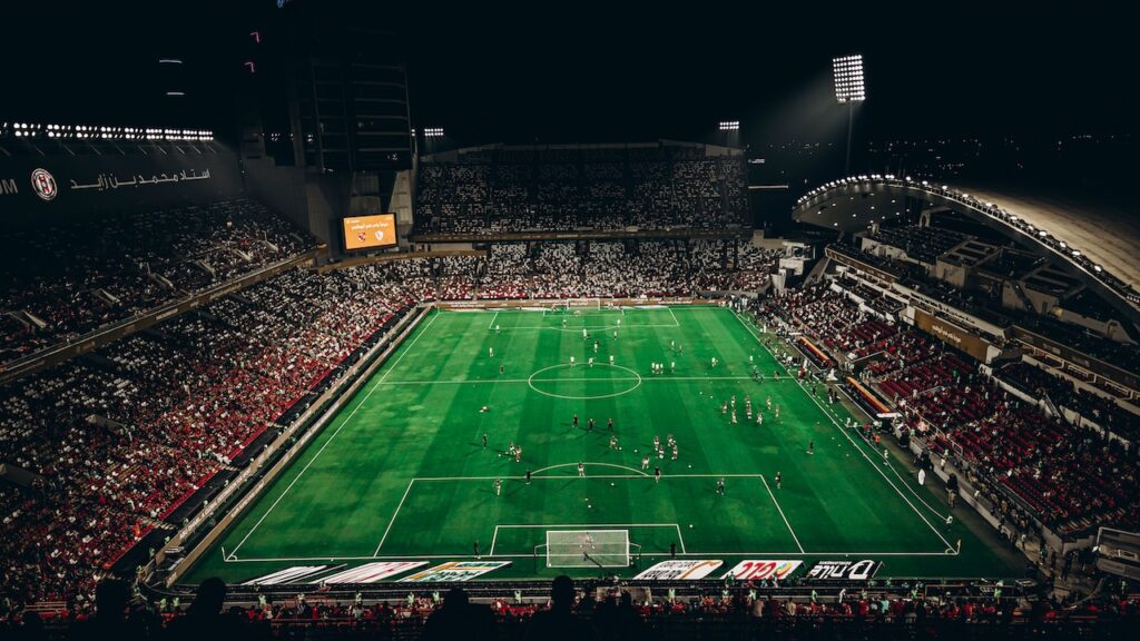 Partida de futebol sendo disputada em estádio