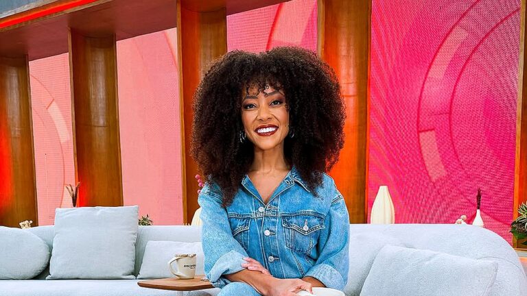 Valéria Almeida sorri no cenário do Encontro usando conjunto jeans durante gravação do programa da TV Globo