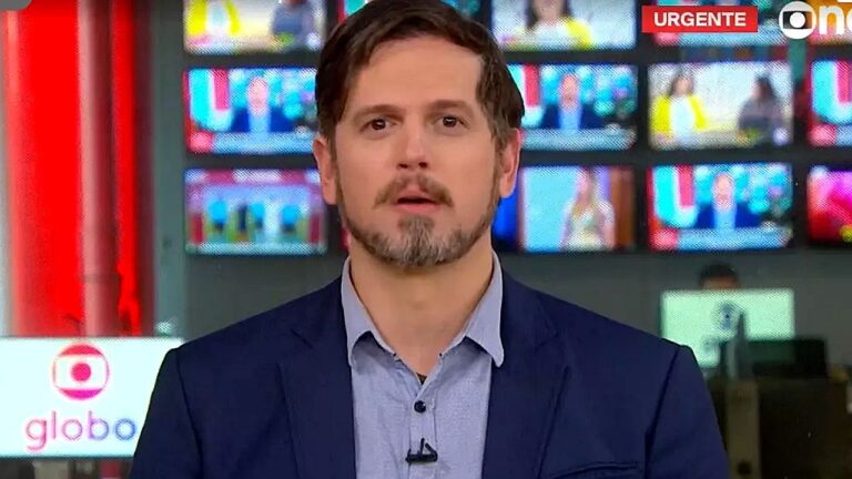 Vinícius Leal apresenta plantão de notícias da GloboNews em frente ao telão da redação da emissora