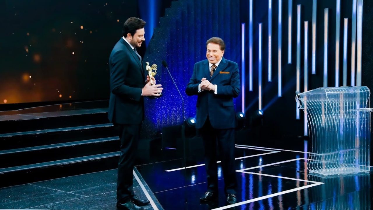 Imagem com foto de Danilo Gentili ao lado de Silvio Santos recebendo estatueta do Troféu Imprensa