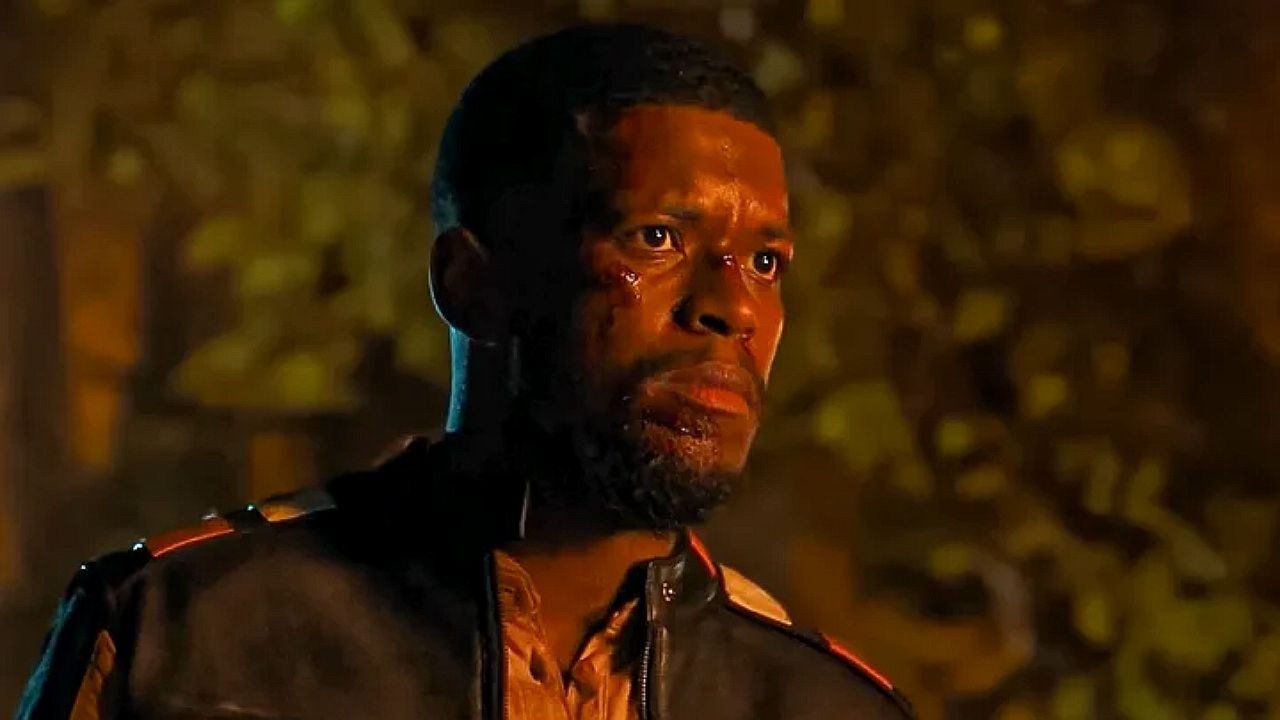 Homem com rosto suado e expressão tensa encara algo à frente em cena noturna com iluminação alaranjada