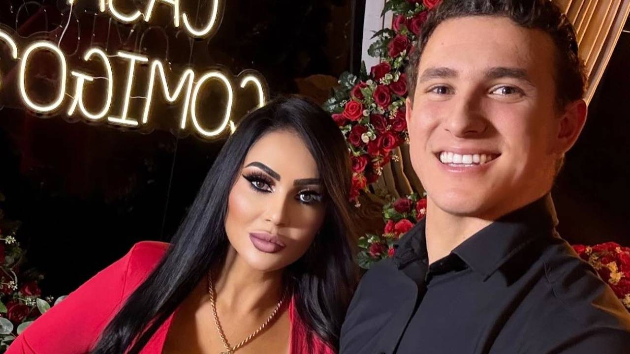 Ana Paula Oliveira e David Maia sorrindo em enquadramento fechado com rosas vermelhas e luz neon