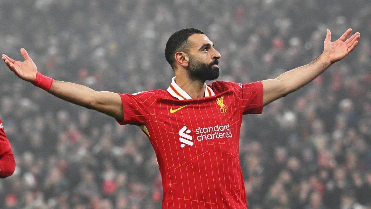 Mohamed Salah barbudo com camisa vermelha do Liverpool em intensa celebração e olhar fixo no estádio