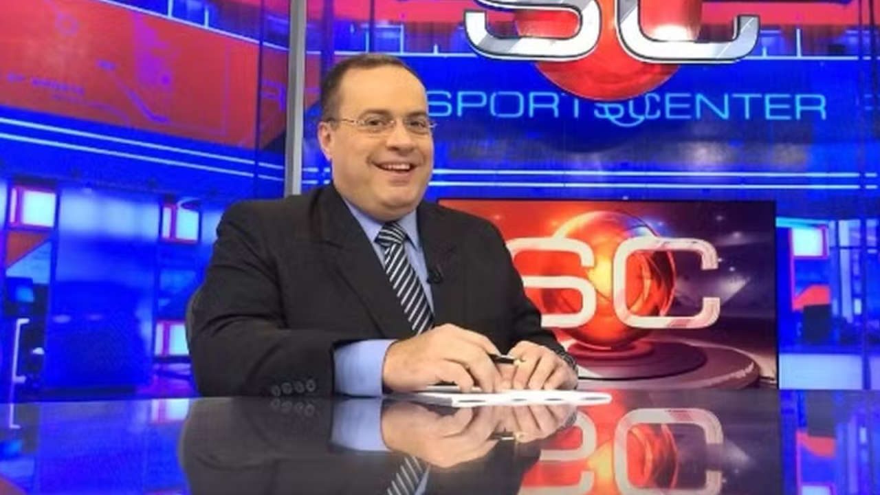 Jornalista Paulo Soares, com terno preto e gravata listrada, sorrindo na bancada do Sportscenter da ESPN com fundo azul e vermelho