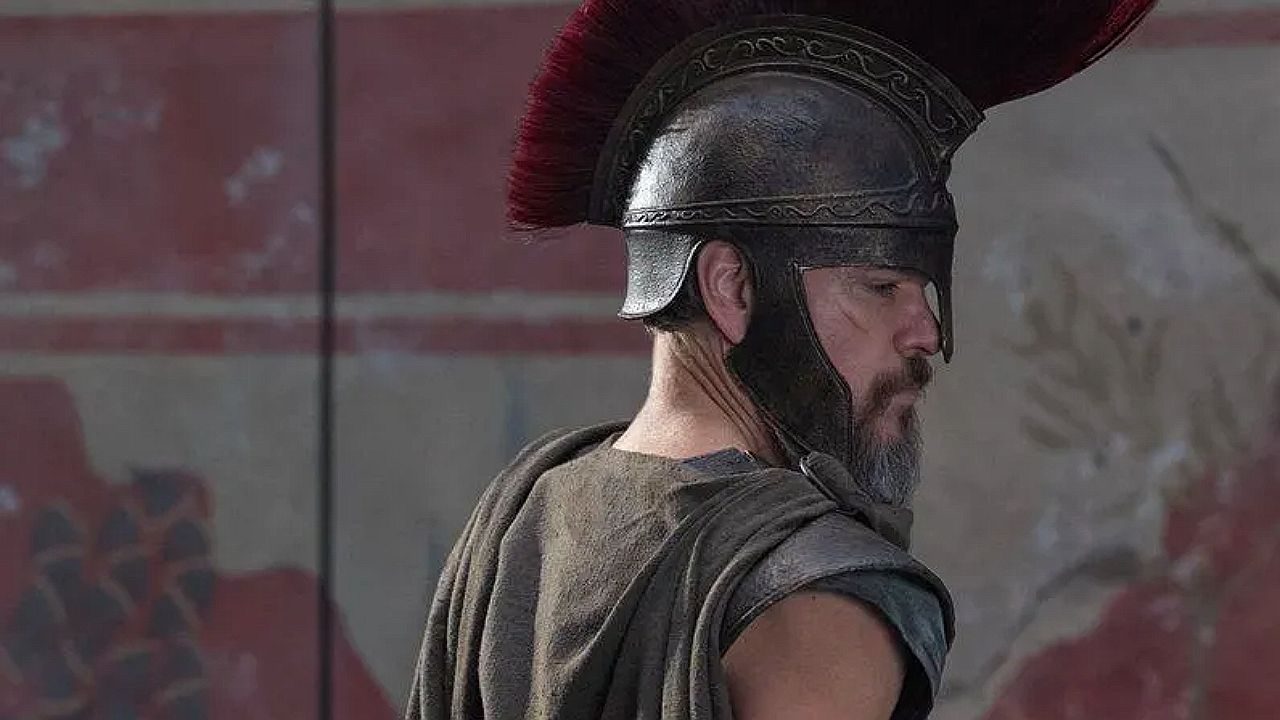Guerreiro com capacete de crista vermelha visto de perfil em cena do filme A Odisseia