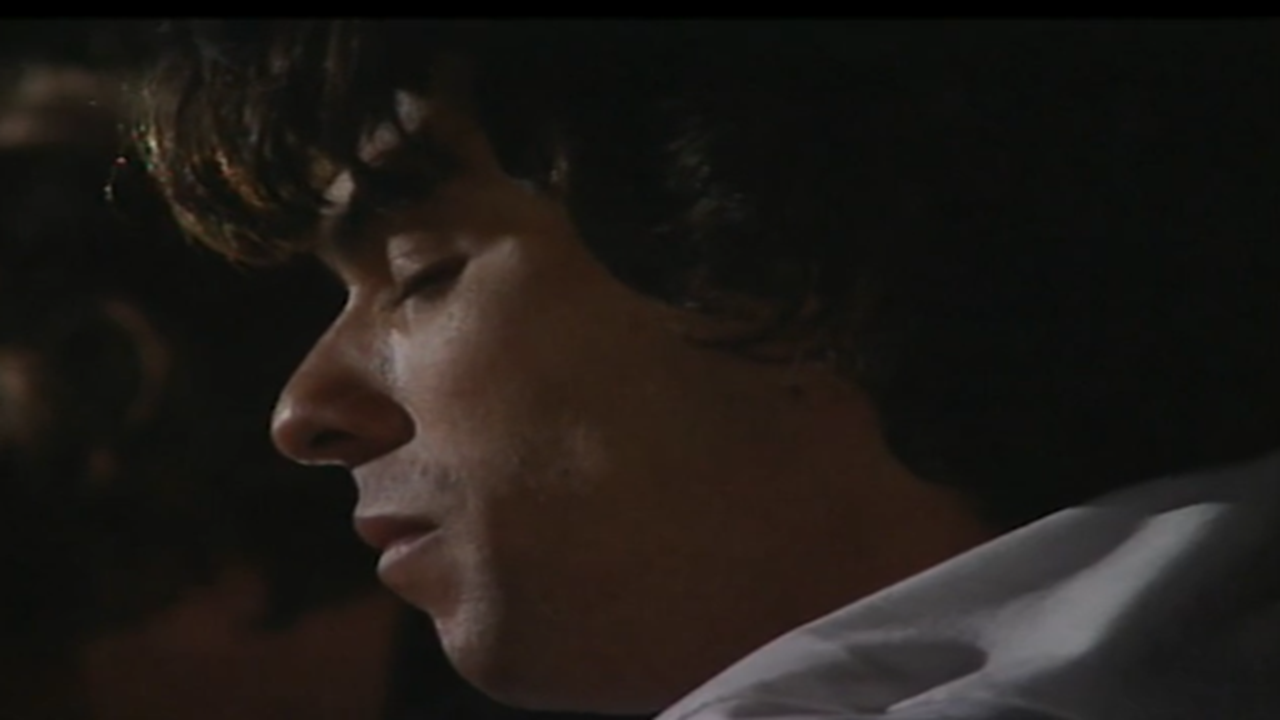 Cena da novela A Viagem mostra um homem de olhos fechados em close, com expressão séria e iluminação suave e escura