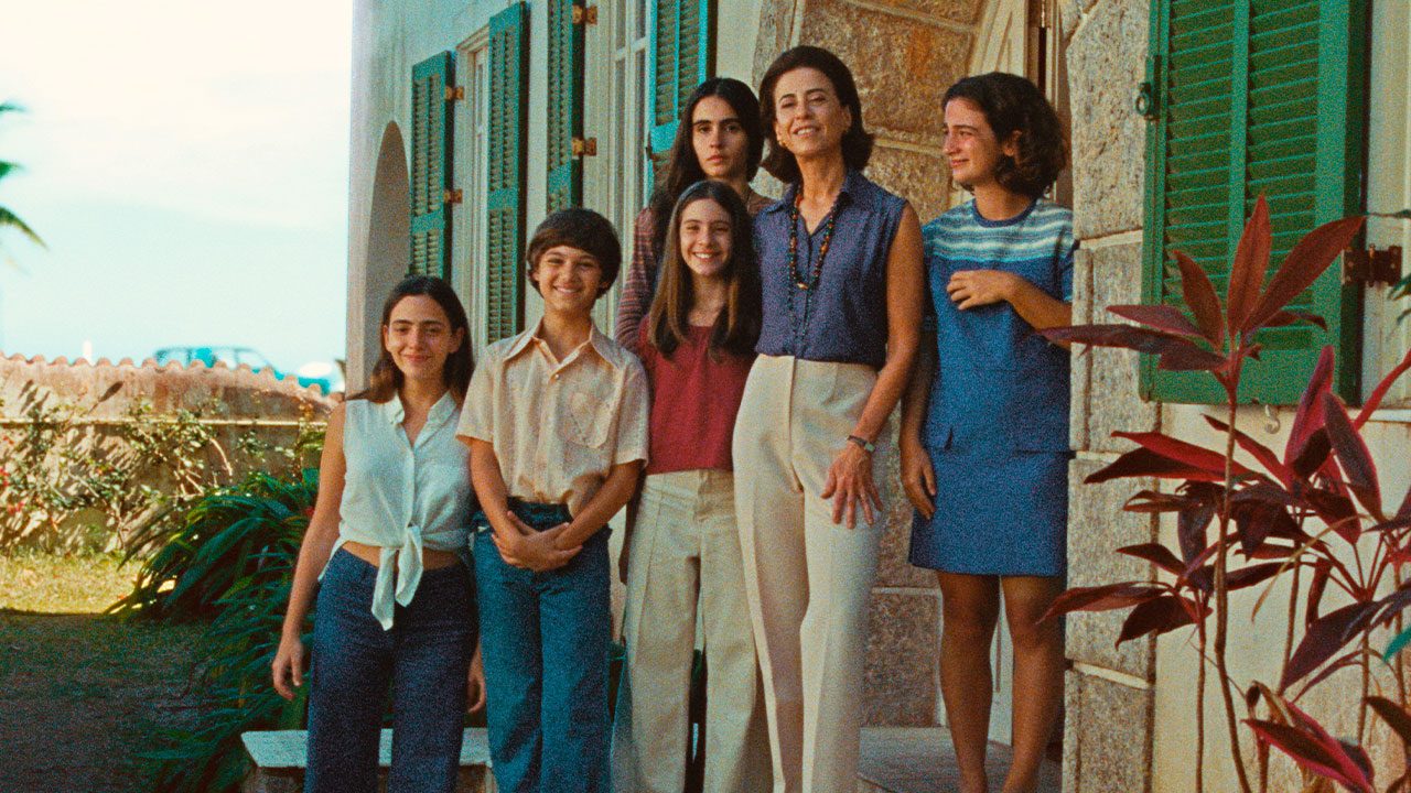 Elenco do filme Ainda Estou Aqui posando em frente a casa com janelas verdes em cena externa