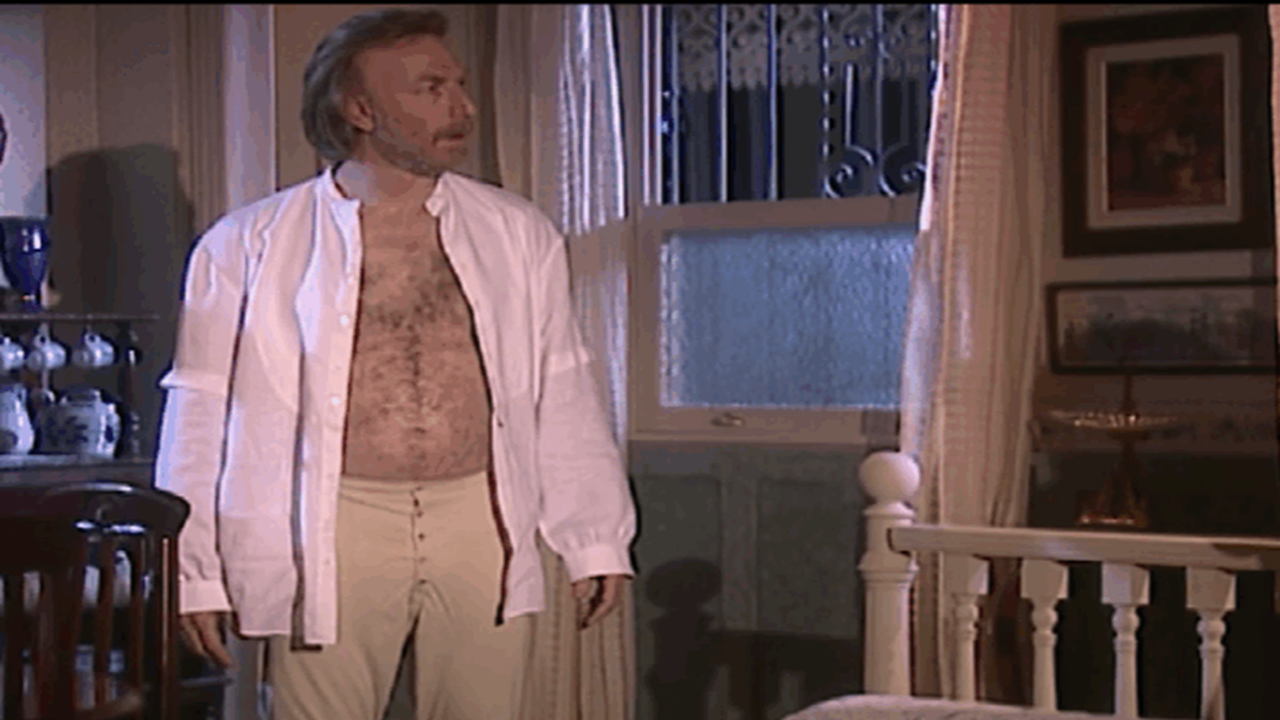 Altino com camisa aberta em quarto durante cena da novela Terra Nostra