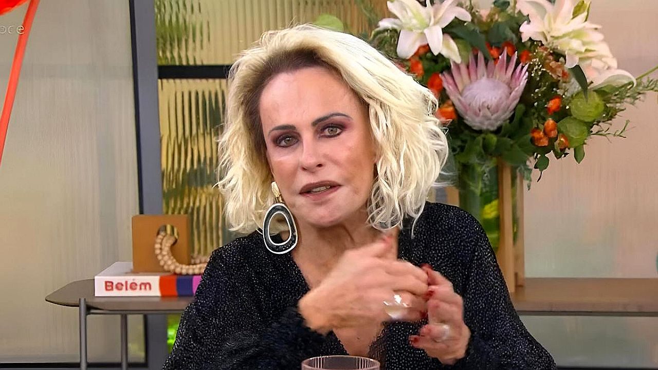 Ana Maria Braga fala durante entrevista no Mais Você com arranjo de flores ao fundo no estúdio da TV Globo