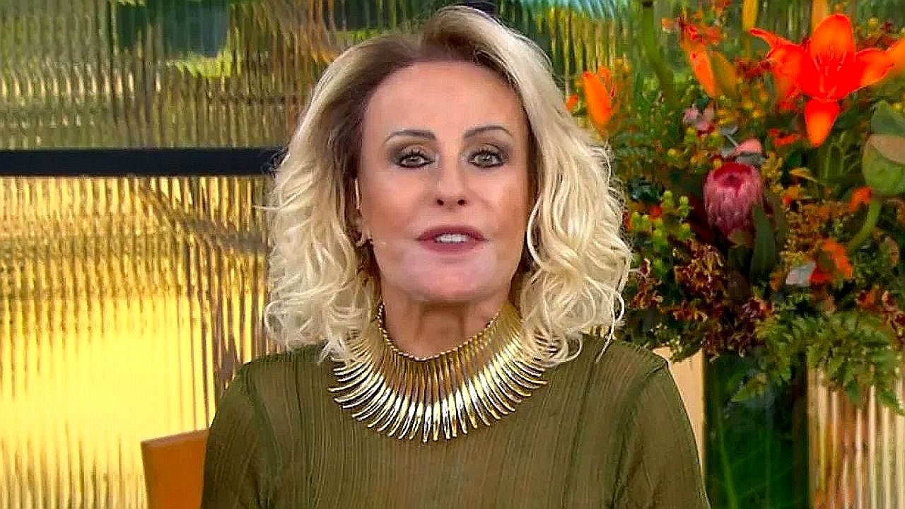 Ana Maria Braga apresenta o Mais Você usando vestido verde e colar dourado diante de arranjo de flores no estúdio