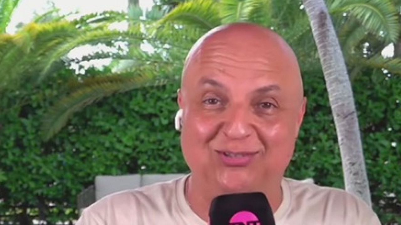 André Henning fala ao microfone durante entrada ao vivo com fones de ouvido e jardim ao fundo