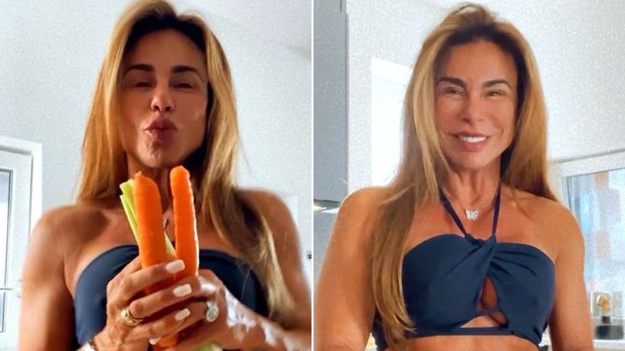 Andrea Sunshine conhecida como vovó fitness aparece de top preto segurando cenouras e salsão em vídeo caseiro na cozinha