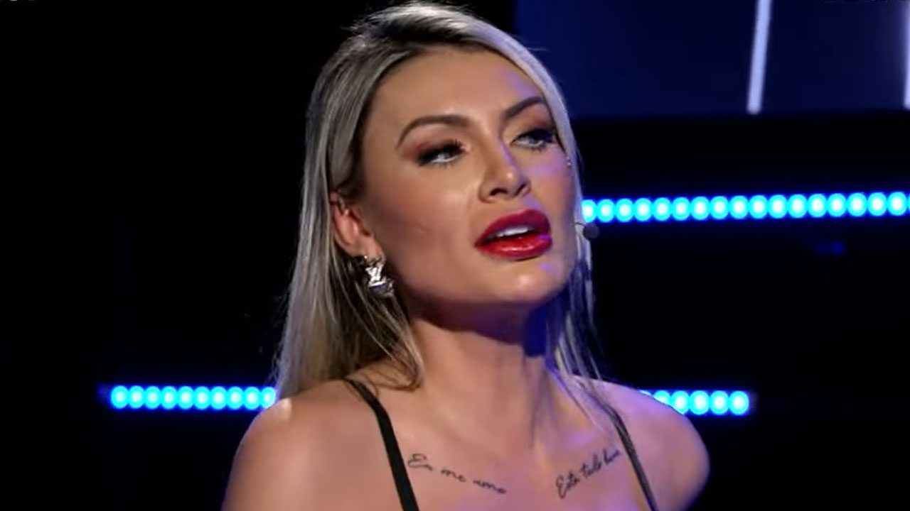 Andressa Urach participa do De Frente com Blogueirinha com expressão séria e iluminação azul ao fundo