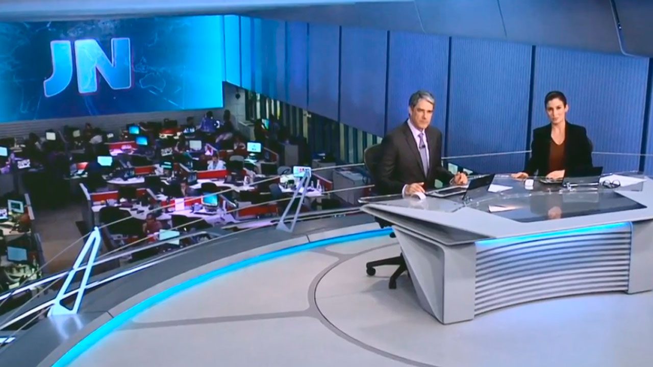 William Bonner e Renata Vasconcellos na bancada do Jornal Nacional com redação da Globo ao fundo