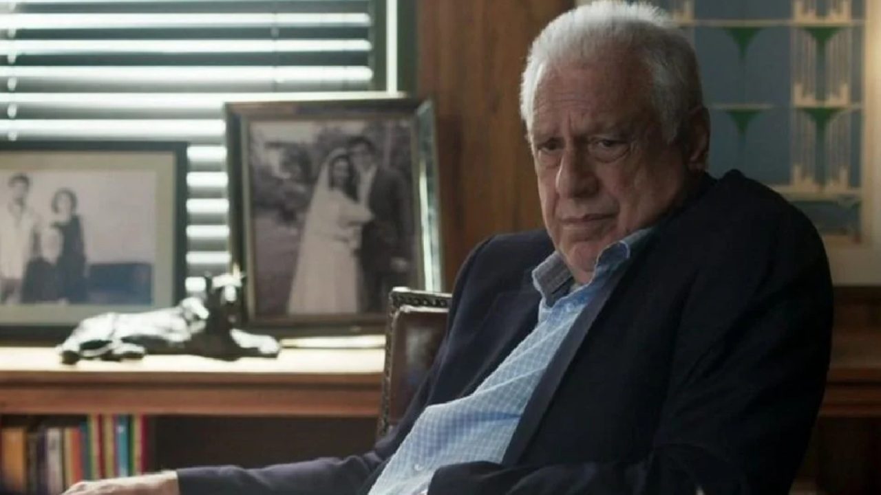 Antonio Fagundes caracterizado como personagem sentado em escritório em cena de novela da TV Globo