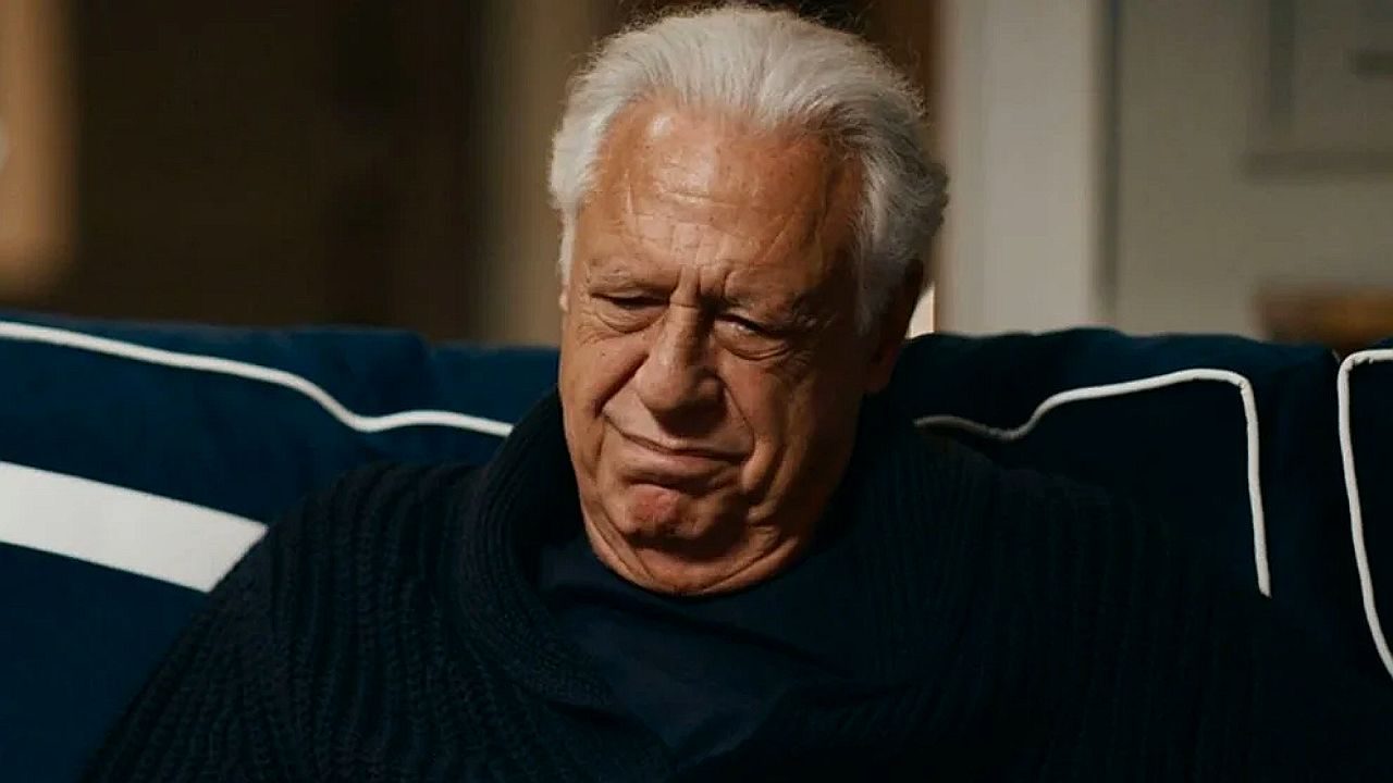 Antonio Fagundes com expressão séria sentado no sofá em cena de série dramática exibida na televisão brasileira