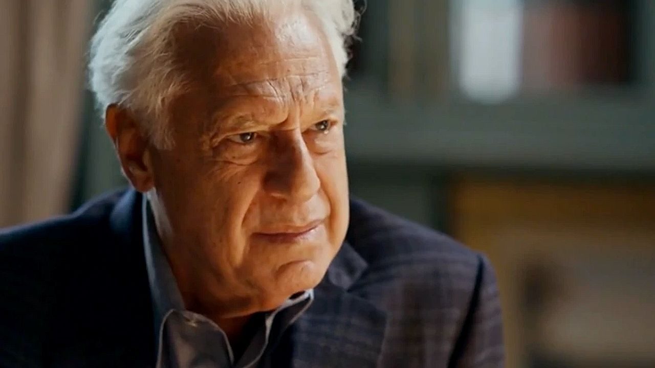 Antonio Fagundes em cena da série Quem Ama Cuida com expressão séria durante conversa em ambiente interno