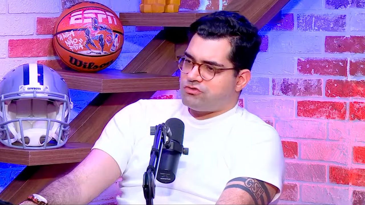 Antony Curti, comentarista da ESPN, falando ao microfone durante o podcast Semana NFL com cenário esportivo ao fundo