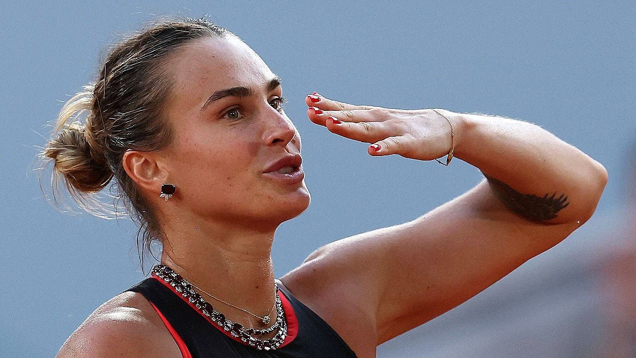 Aryna Sabalenka celebra ponto durante partida de tênis com gesto de saudação à torcida em quadra profissional