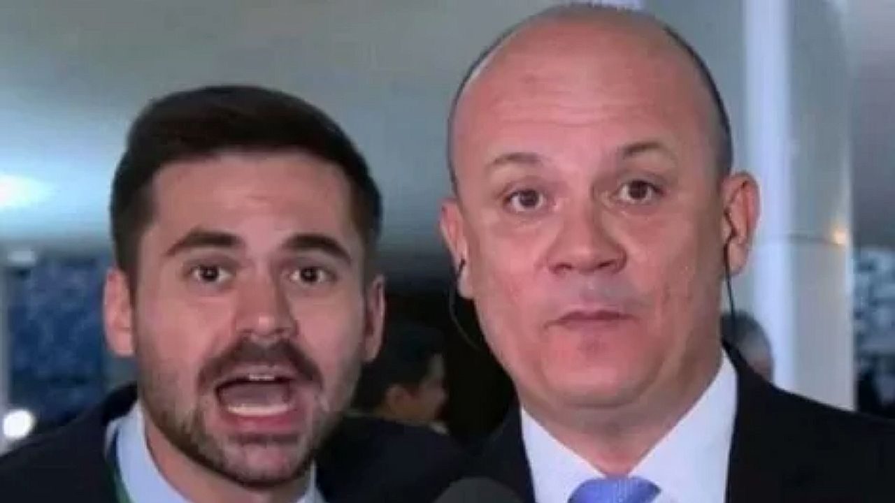 Dois repórteres aparecem em transmissão ao vivo falando para a câmera em ambiente interno com microfone e ponto eletrônico