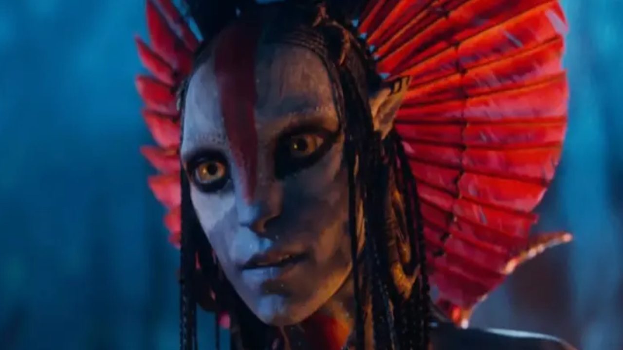 Personagem azul com olhos amarelos e adereço vermelho na cabeça em cena de filme de ficção ambientada à noite