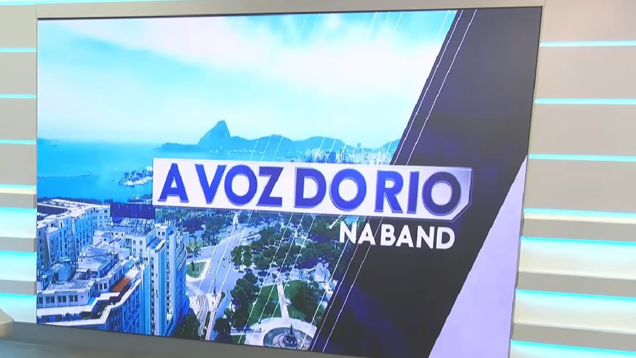 Tela de estúdio exibe o logotipo do programa “A Voz do Rio na Band” com imagem aérea do Rio de Janeiro ao fundo